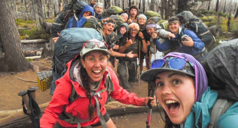 a group of students smile excitedly while backpacking on an outward bound trip